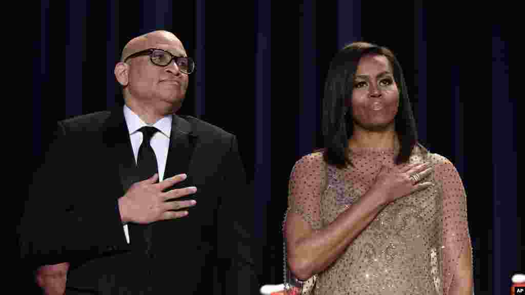 Larry Wilmore, left, guest host from Comedy Central, and first lady Michelle Obama listen to the National Anthem at the annual White House Correspondents' Association dinner at the Washington Hilton in Washington, April 30, 2016. 