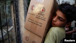 A boy unloads aid parcels in the rebel-held besieged town of Zamalka, in the Damascus suburbs, Syria, June 29, 2016. 