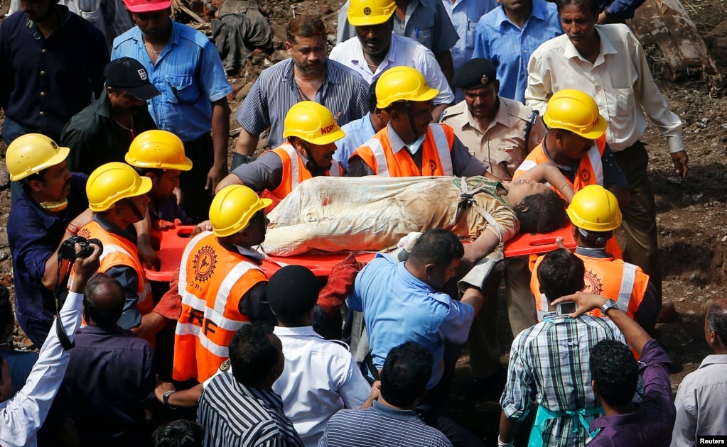 Rescue workers use a stretcher to carry a woman who was rescued from the rubble at the site of a collapsed residential building in Mumbai, Sept. 27, 2013. 