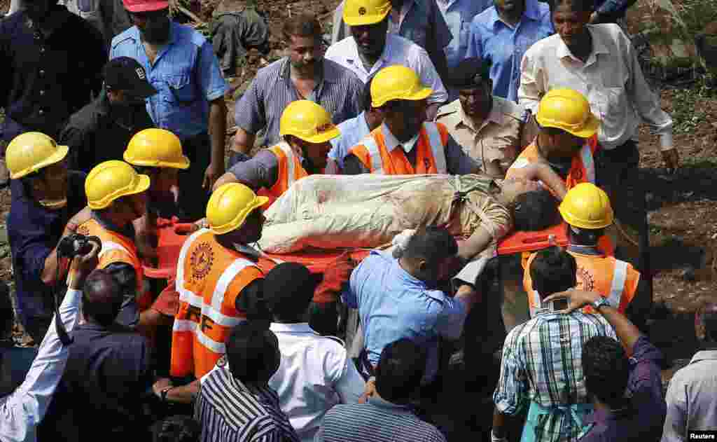 Rescue workers use a stretcher to carry a woman who was rescued from the rubble at the site of a collapsed residential building in Mumbai, Sept. 27, 2013. 