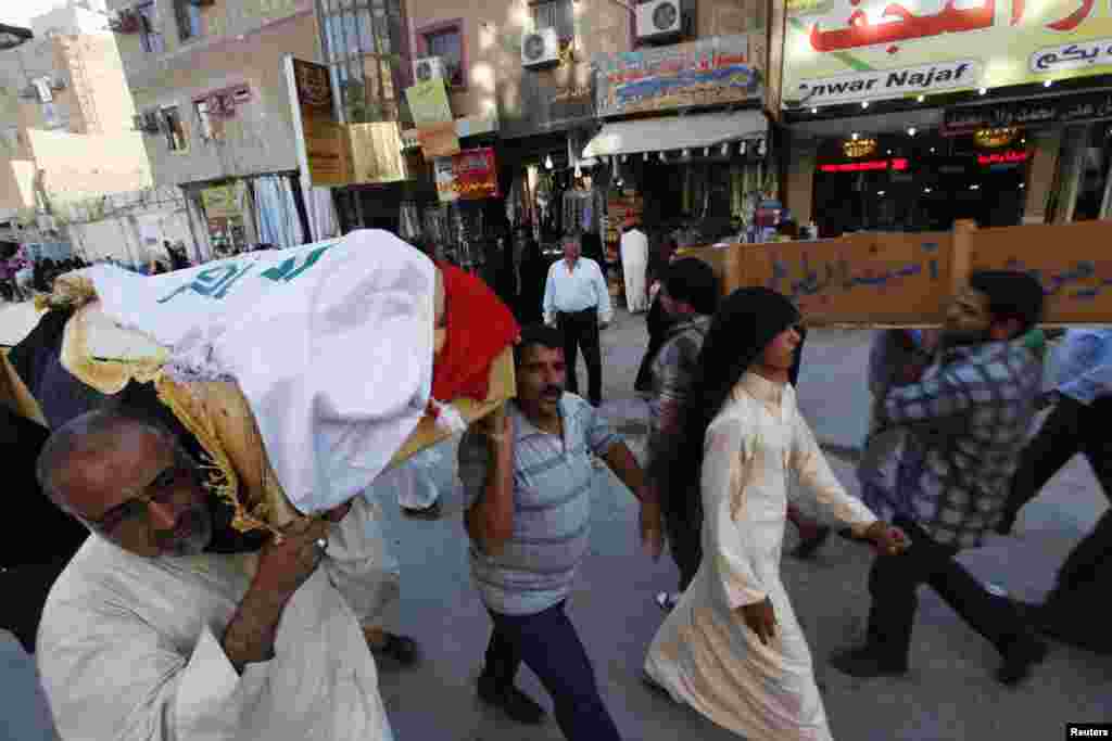 Mourners carry the coffin of a police officer who was killed in a Basra car bomb attack during a funeral in Najaf, Iraq, June 16, 2013.