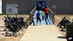 FILE - Photo provided by U.S. Immigration and Customs Enforcement shows immigrants walking into a building at South Texas Family Residential Center in Dilley, Texas.