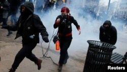 Para demonstran berlarian setelah polisi mempergunakan gas airmata dan granat kejut untuk membubarkan protes anti Trump di Washington DC, hari Jumat (20/1).