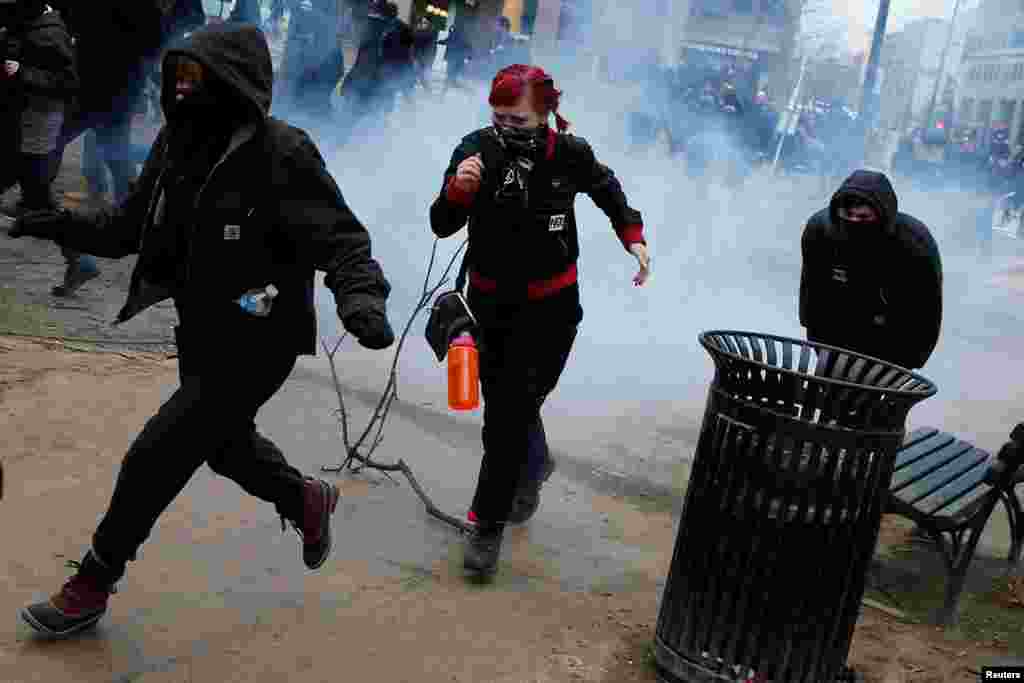 Activists run after being hit by a stun grenade while protesting against U.S. President Donald Trump on the sidelines of the inauguration in Washington, DC, U.S., January 20, 2017. REUTERS/Adrees Latif