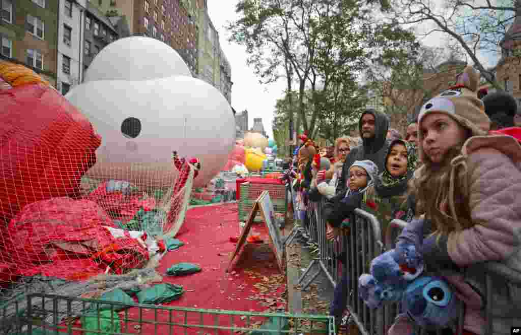 Las multitudes se reúnen para ver globos de personajes gigantes, que se inflan la noche antes de su aparición en el desfile.