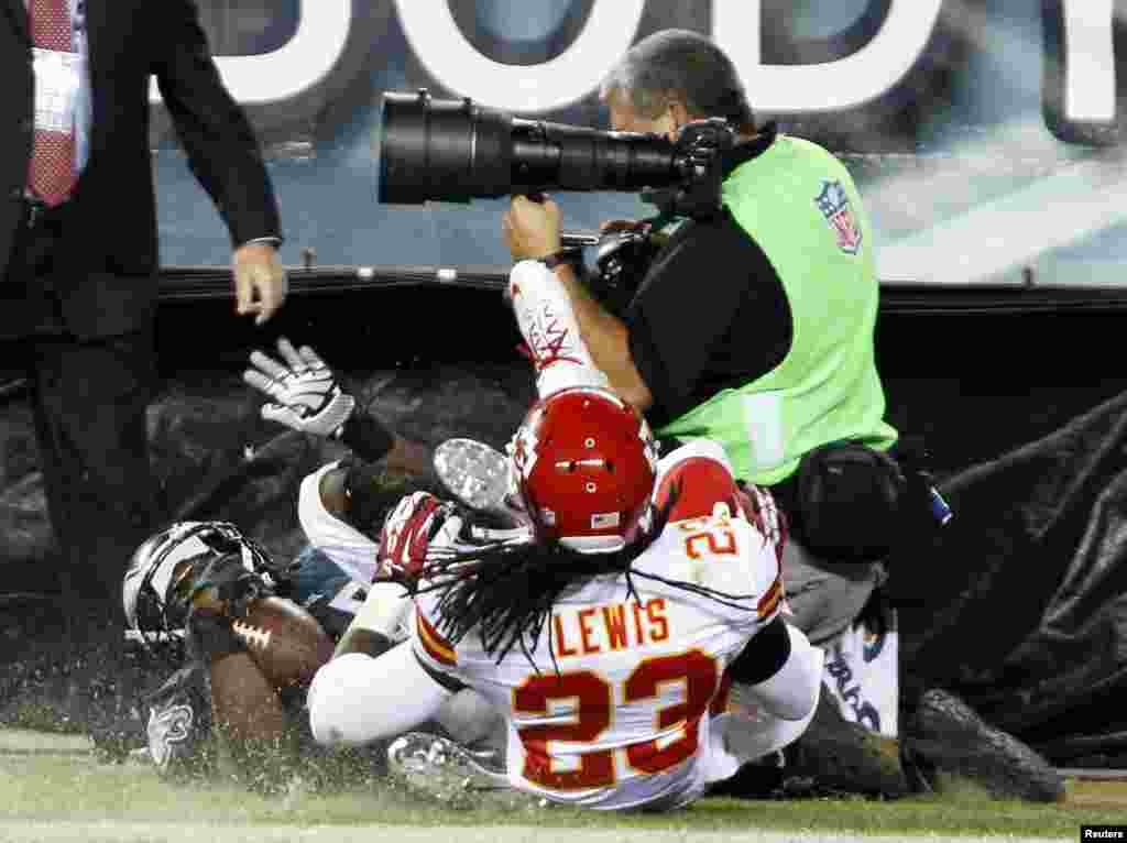 Philadelphia Eagles&#39; LeSean McCoy (25) and Kansas City Chiefs&#39; Kendrick Lewis (23) roll into a photographer on the sidelines after McCoy scored a touchdown during the fourth quarter of the NFL football game in Philadelphia, Pennsylvania, Sept. 19, 2013.