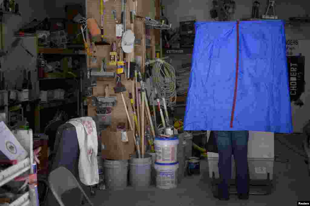 A voter casts his ballot inside the garage of Chobert Decorators during the U.S. presidential election in Philadelphia, Pennsylvania.