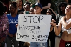 People hold signs during a protest in front of the El Cajon Police Department in El Cajon, California, Sept. 28, 2016.