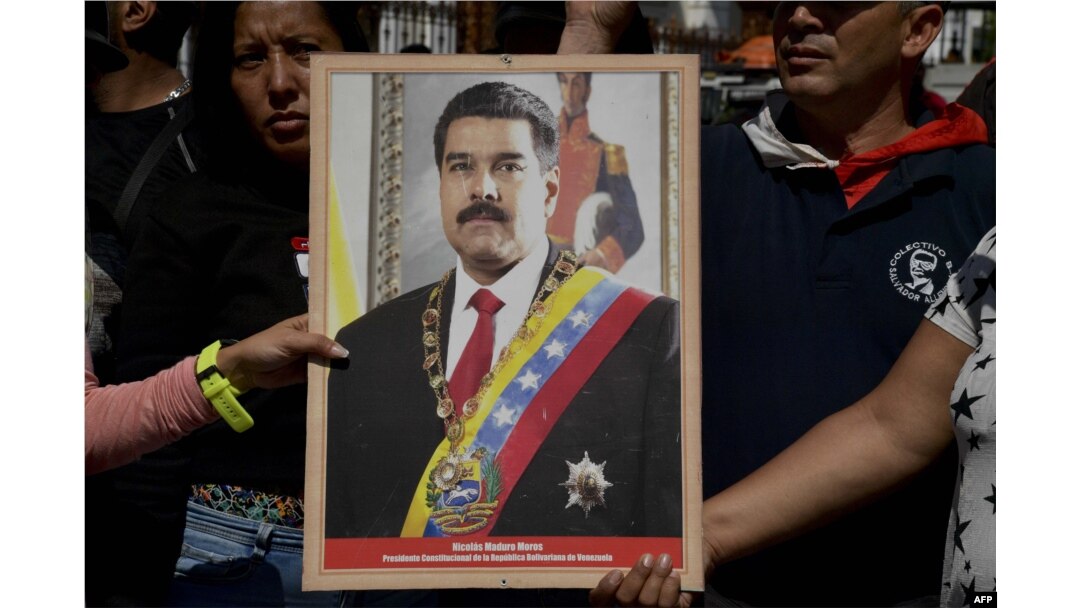 Supporters of Venezuelan President Nicolas Maduro hold a portrait of him in a ceremony to swear him in symbolically in front of the National Assembly building during a rally around the city in Caracas, Venezuela on Jan. 7, 2019.