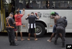 FILE - Police search bus commuters on their way to Copacabana beach in Rio de Janeiro, Brazil, Sept. 26, 2015.
