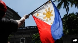 FILE - A protester waves a Philippine flag during a rally outside the Department of Foreign Affairs in Manila, Philippines on Friday, June 21, 2019.
