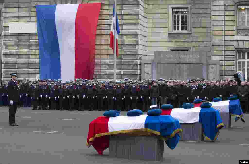 French Police officers pay respects to the three officers killed during last week&#39;s terror attacks during a national tribute at Paris Prefecture.