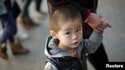 A boy walks with his grandmother at a commercial area of downtown Shanghai, November 28, 2012. 