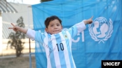 Murtaza Ahmadi argentinalı futbol ulduzu Lionel Messinin imzaladığı futbol köynəyi ilə şəkil çəkdirərkən.