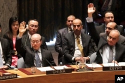 FILE - Chinese ambassador to the United Nations Liu Jieyi, left, and Egypt ambassador to the U.N. Abdellatif Aboulatta, right, vote on a resolution during a Security Council meeting at U.N. headquarters, Wednesday, March 2, 2016.