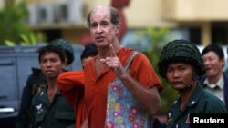 FILE - Australia filmmaker James Ricketson, center, ) speaks to the media at the Supreme Court in Phnom Penh, Cambodia, Jan. 17, 2018.