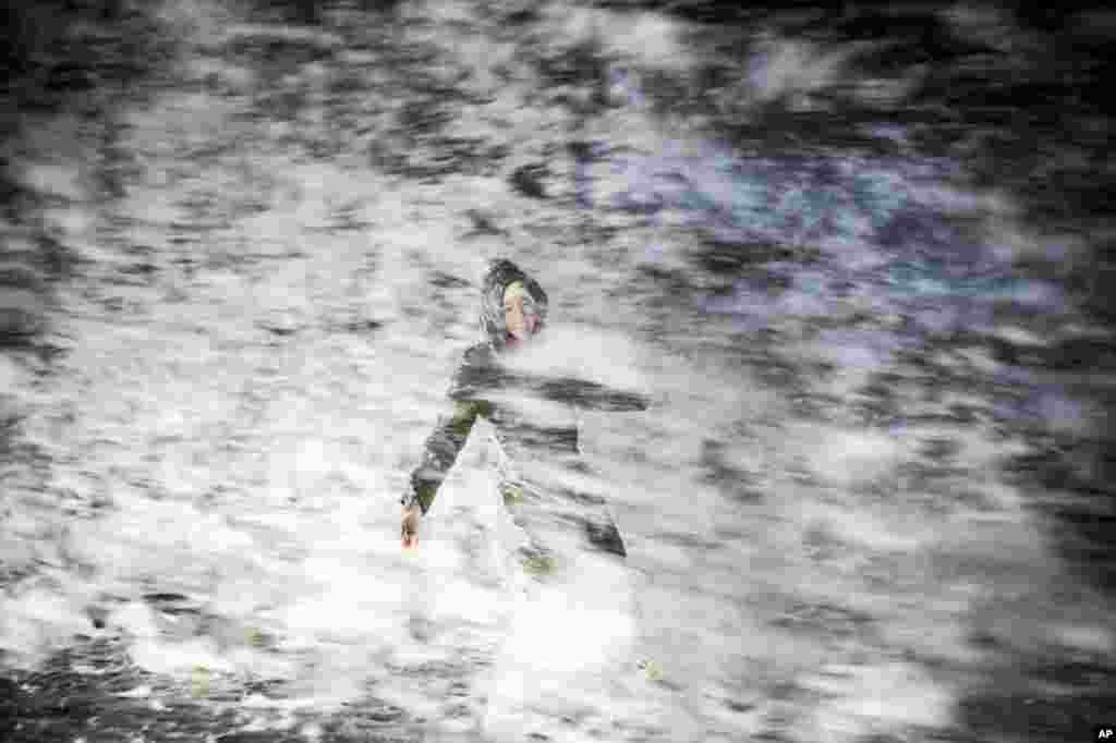 A woman gets splashed as she walks on the coast, in Hirtshals, the northern part of Jutland, Denmark, Dec. 26, 2016.