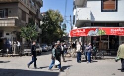 Warga Suriah berjalan di sepanjang pasar terbuka di pusat kota Homs, Suriah, 7 April 2017. (Foto: STRINGER / AFP)