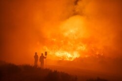 Petugas pemadam kebakaran beupaya memadamkan api akibat kebakaran hutan antara Navlacruz dan Riofrio dekat Avila, Spanyol tengah, 16 Agustus 2021. (AFP)