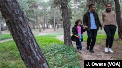 Reham (left), her father Ammar and Adonis walk through their local park.