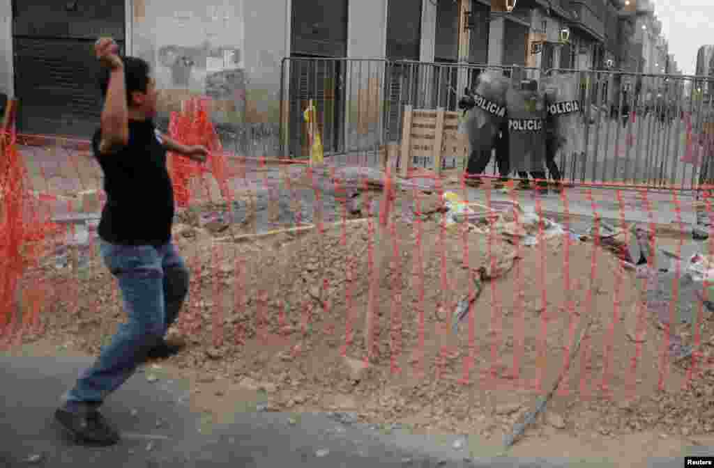 Un manifestante arroja piedras a los agentes de la policía antidisturbios durante una protesta que exige elecciones presidenciales y el cierre del Congreso después de que el derrocado líder peruano Pedro Castillo fuera detenido en una prisión policial tras su destitución, en Lima, Perú, el 8 de diciembre de 2022. REUTERS/ Sebastián Castañeda