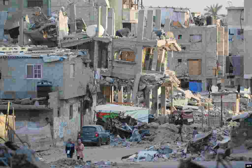 People walk past destroyed buildings in Khan Yunis in the southern Gaza Strip.