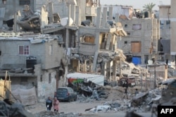 People walk past destroyed buildings in Khan Yunis in the southern Gaza Strip, Oct. 17, 2024.