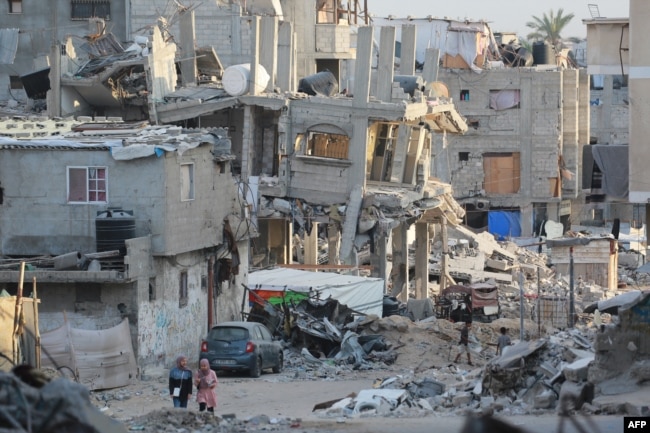 People walk past destroyed buildings in Khan Yunis in the southern Gaza Strip, Oct. 17, 2024.