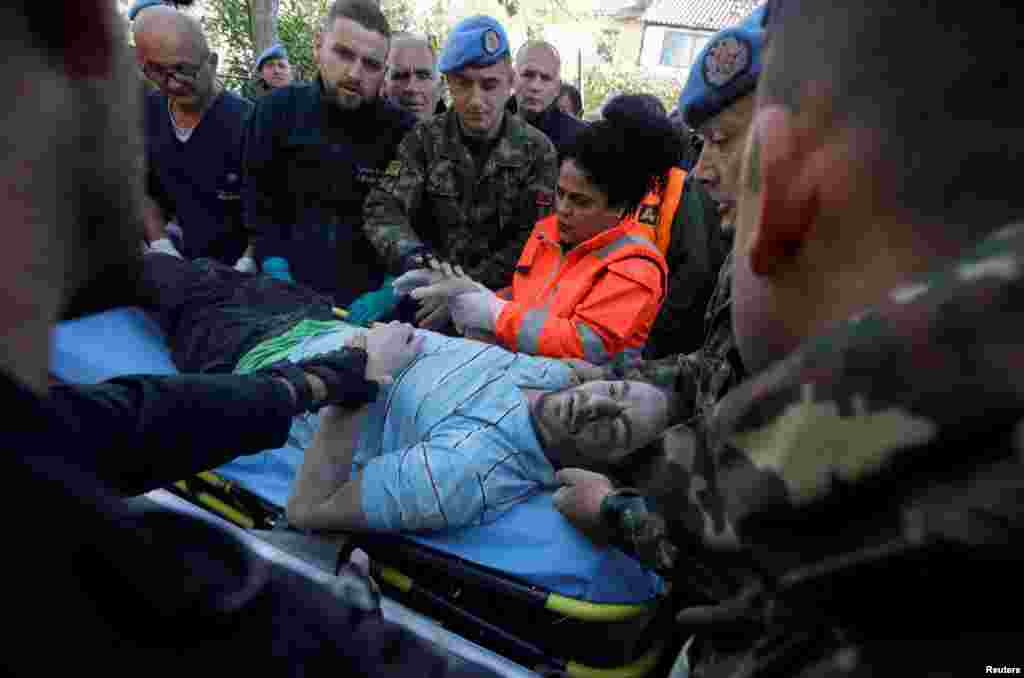Military and emergency personnel helps an injured man in Thumane, after an earthquake shook Albania, Nov. 26, 2019.