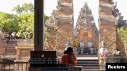 Seorang perempuan menunggu para wisatawan di Pura Puseh, Desa Batuan, Gianyar, Bali, 5 Februari 2020. (Foto: Reuters)