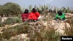 Des migrants sont assis devant le centre d’immigration sur l’île de Lampedusa, dans le sud de l’Italie, le 19 février 2015.