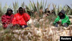 Des migrants assis sur une colline à l'extérieur du centre d'immigration sur l'île de Lampedusa, au sud de l'Italie, 19 février 2015.