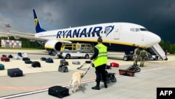 A Belarusian dog handler checks luggages off a Ryanair Boeing 737-8AS (flight number FR4978) parked on Minsk International Airport's apron in Minsk, on May 23, 2021. (ONLINER.BY / AFP)