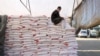 A Palestinian worker rests on a stack of flour at an aid distribution centre in the southern Gaza Strip city of Khan Yunis on December 3, 2024.