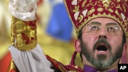 FILE - Armenian Archbishop Khajag Barsamian pours holy oil from a dove-shaped vessel during the Ceremony of the Blessing of the Water, during Christmas services.