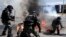 A protester, bottom, and riot policeman react after catching fire from a gasoline bomb during a protest in the the northern city of Thessaloniki, Greece.
