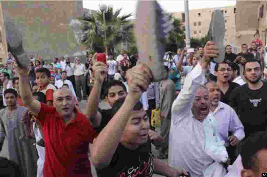 Protesters raise their shoes as they heckle Egyptian presidential candidate Ahmed Shafiq, unseen, as he arrives to vote at a polling site in Cairo, Egypt, Wednesday, May 23, 2012. Presidential Candidate and former Egyptian Prime Minister Ahmed Shafiq was 