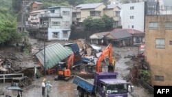 Mangled houses and other debris swept away by a landslide are seen by a road following days of heavy rain in the Izusan area of Atami in Shizuoka Prefecture on July 4, 2021. (Photo by STR / JIJI PRESS / AFP) / Japan OUT