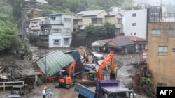 Mangled houses and other debris swept away by a landslide are seen by a road following days of heavy rain in the Izusan area of Atami in Shizuoka Prefecture on July 4, 2021. 