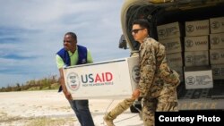 Le caporal américain Steven Arroyo aide un représentant de l'Organisation internationale pour les migrations à transporter du matériel à Jeremie, Haïti, 9 octobre 2016.