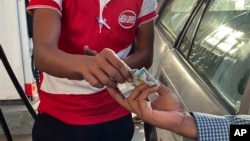 FILE - A driver hands over Myanmar kyats to an attendant as payment for fuel at a gas station in Yangon, Myanmar, on Nov. 12, 2021. The kyat was trading on the black market for more than 4,500 to the dollar in May 2024.