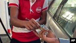 Seorang pengendara menyerahkan lembaran mata uang Myanmar kyats sebagai pembayaran di sebuah pom bensin di Botahtaung, Yangon, Myanmar, pada 12 November 2021. (Foto: AP)