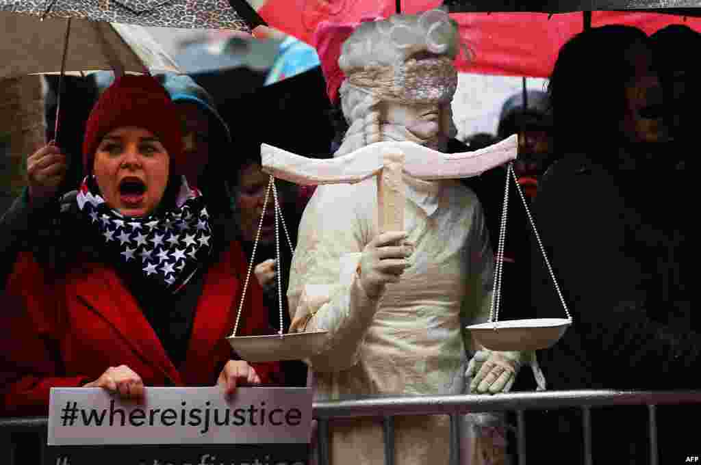 A woman dressed as Lady Justice joins over 100 protesters, many of them women, at a rally in heavy rain outside of the offices of Democratic Senators Chuck Schumer and Kirsten Gillibrand to demand that they hold up the nomination process of President Donald Trump&#39;s cabinet choices, in New York City.