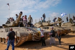 Israelis stand on tanks during an event for families of reservists outside a military base in southern Israel, Feb. 27, 2024.