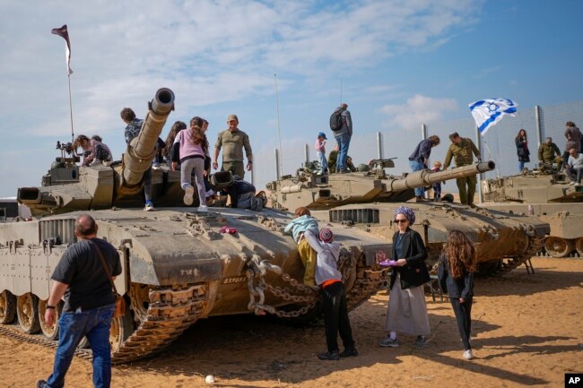 Israelis stand on tanks during an event for families of reservists outside a military base in southern Israel, Feb. 27, 2024.