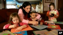 Au pair Wendy Aguirre helps the Lyon children Ella, right; C.J., left; and Jackson with art projects Thursday, Dec. 7, 2006, in Overland Park, Kan. Aguirre, from Panama, is teaching the three 3-year-olds Spanish as part as her duties as the family's au pa