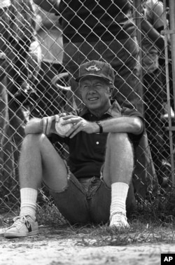 Presiden Jimmy Carter mengenakan celana jins, kemeja olahraga, dan sepatu tenis sambil menunggu giliran untuk memukul bola melawan tim softball saudaranya Billy di Plains, Ga., 19 Agustus 1978. (Jim Wells/AP)