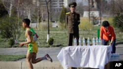 A North Korean military soldier stands on duty while a participant of the Pyongyang marathon runs past a water station, April 9, 2017, in Pyongyang, North Korea. Hundreds of foreigners took to the streets of Pyongyang Sunday for an annual marathon that has become one of the North Korean capital's most popular tourist events. 