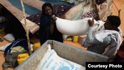 A recently arrived refugee from Mali is helped loading her rations of rice, oil and sugar onto a truck at the M'Berra refugee camp for Malian refugees in southeastern Mauritania, March 2, 2013. (Nyani Quarmyne/MSF)