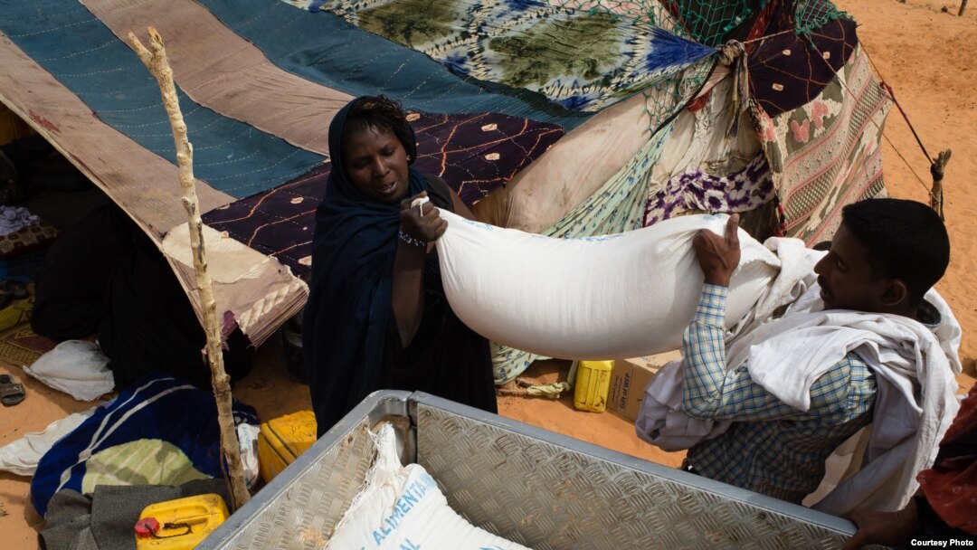 Un nouveau refugiée venu du Mali aident à transporter des sacs du riz, de l’huile et du sucre sur un véhicule dans le camp de M’Bera, dans la sud de la Mauritanie, 2 mars 2013.